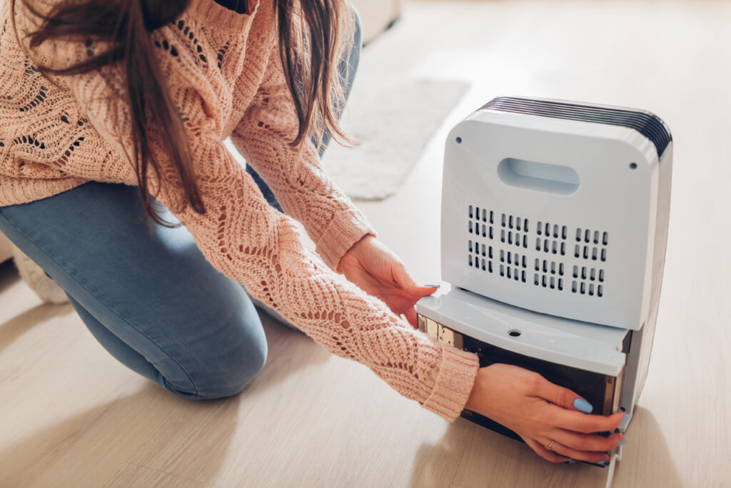 Woman changing water container of dehumidifier